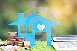 Mortgage calculator, Blue house model and stack of coins money on natural green background,Interest rates and Banking concept