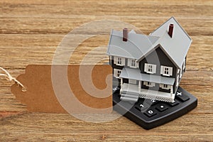 Mortgage calculator and gift tag with a house on a wood desk