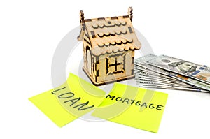 Mortgage concept with a toy house and dollars on a white background. Stickers with the word `mortgage`, `loan`