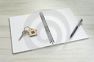 Mortgage, debt or property loan, white blank page of notepad and pen on the right hand side, key with house key chain on the left