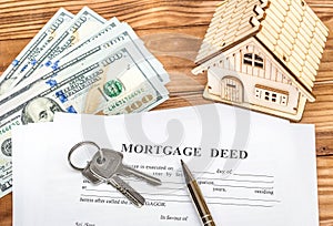 Mortgage deed with keys, money and model of house on the table