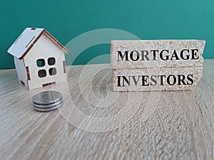 Mortgage investors symbol. Concept words \'Mortgage investors\' on brick blocks near miniature wooden house.