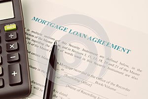 Mortgage loan agreement sign contract concept, pen with calculator on mortgage form or contract, long term debt, home and house o