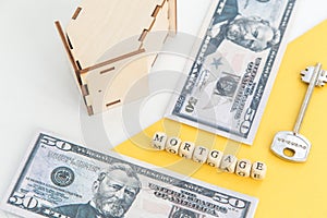 mortgage, loan and home purchase. Model of house, dollar bills, key on white and yellow isolated background. Free space for text,