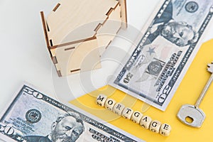 mortgage, loan and home purchase. Model of house, dollar bills, key on white and yellow isolated background. Free space for text,