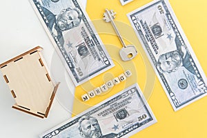 mortgage, loan and home purchase. Model of house, dollar bills, key on white and yellow isolated background. Free space for text,