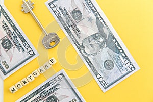 mortgage, loan and home purchase. Model of house, dollar bills, key on white and yellow isolated background. Free space for text,