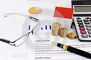 Mortgage loans concept with close up or Fountain pen and coins stack and paper house and calculator and glasses on loans request f