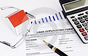 Mortgage loans concept with fountain pen and eyeglasses and paper house and calculator and loan application form document