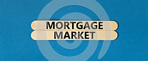 Mortgage market symbol. Concept words Mortgage market on beautiful wooden stick. Beautiful blue table blue background. Business