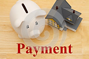 Mortgage payment message with a model house with a piggy bank