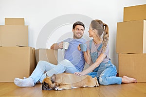 Happy couple with boxes and dog moving to new home