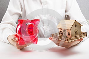 Mortgage or savings concept. hands holding money box and miniature house