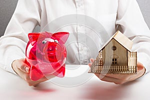 Mortgage or savings concept. hands holding money box and miniature house