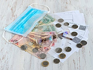 Mortgage and utility bills, coins and Arabic dirhams banknotes, glasses and medical mask, soft focus.