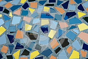 Mosaic of broken tiles on grey background outside. Textured colourful floor