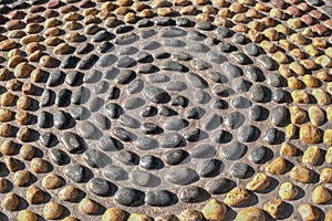 Mosaic circle pattern from convex rounded pebble stones. Ground path textured surface from boulders.Reflexology stones