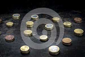 Mosaic with a regular pattern made up of euro coins on a dark black background with metal details