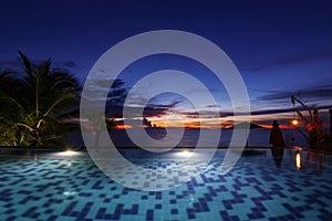 Mosaic swimming pool in sea front hotel resort with ocean sea beach and twilight sky background landscape in Thailand