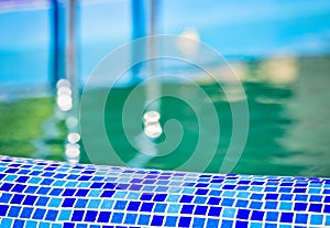 Mosaic swimming pool sidel with blurred stairs and water. Outdoor swimming pool background