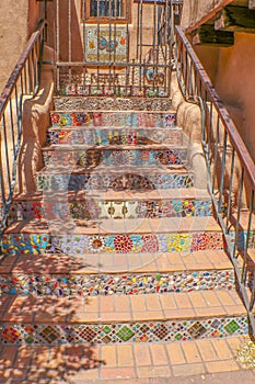 Mosaic and tile steps leading up from the street to an iron gate