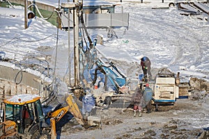 MOSCOW, FEB. 01, 2018: Winter view on dirty heavy construction equipment, vehicles workers at work. Drilling operations on constru