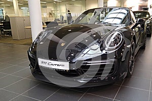 Moscow. February 2018. Black Porsche 911 991 Carrera at dealer showroom. Headlights and aerodynamic turbo packed Front and left