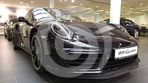 Moscow. February 2018. Black Porsche 911 991 Carrera at dealer showroom. Headlights and aerodynamic turbo packed Front and side