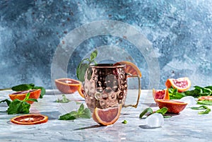 Moscow mule cocktail in copper cup with blood orange, ginger beer, vodka and mint. freeze motion splash