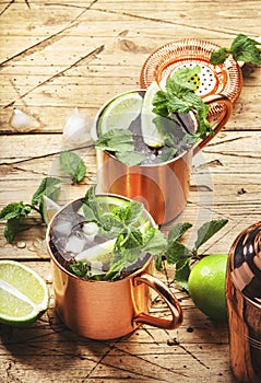 Moscow mule cocktail in copper mug with lime, ginger beer, vodka and mint. Wooden table, top view, copy space