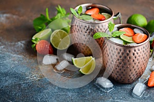 Moscow mule cocktail with ginger beer, vodka, lime, strawberries and mint in a cooper mugs.