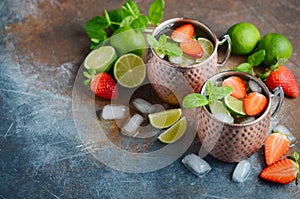 Moscow mule cocktail with ginger beer, vodka, lime, strawberries and mint in a cooper mugs.