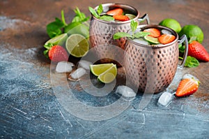 Moscow mule cocktail with ginger beer, vodka, lime, strawberries and mint in a cooper mugs.