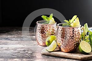 Moscow mule cocktail served with ice and lime slice on wooden table