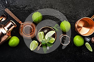 Moscow Mule. Preparation cocktail  with ginger beer, vodka, lime and ice. Copper bar tools. Black bar counter. Top view