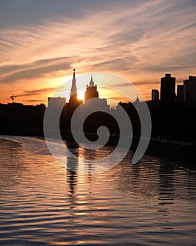 Moscow river, embankment and silhouettes of buildings and Kremlin towers on sunset