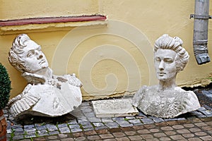 Old plaster busts of a man and woman from the time of 1812 lying on the paving stones in the