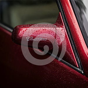 MOSCOW, RUSSIA - AUGUST 26, 2017: Rear view mirror from with logo on a vintage red Cadillac car close-up, selectiv focus