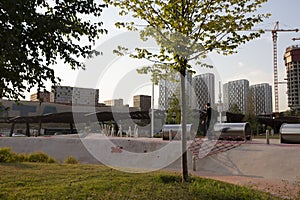 Moscow, Russia - 08.08.2021. Children playground with skate cradle bowl, tubes, net, pergola, beautiful lawn and tree. Tyufeleva R