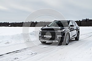 MOSCOW, RUSSIA - FEBRUARY 23, 2021 CHERYEXEED TXL SUV car in motion front side view. Black SUV on nature background