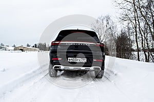 MOSCOW, RUSSIA - FEBRUARY 23, 2021 CHERYEXEED TXL SUV car rear side close up view. Black AWD SUV on winter background