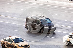 Fast moving Volkswagen Transporter T5 on the city road. Black minivan rides on street. Commercial VW in fast motion