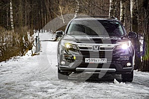 MOSCOW, RUSSIA - FEBRUARY 2, 2020: New Honda SUV Pilot 3 Generation Black in winter off-road. LED head light optics included.