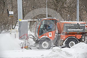 Moscow, Russia, February 13, 2021: Yellow tractor clears snow-covered roads on a city street