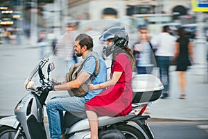 MOSCOW - RUSSIA JULY 02, 2017: young caucasian man is driving a girl on a motorcycle. The girl is dressed in a red dress