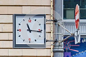 Moscow, Russia - June 02, 2019: Analogue street clock hanging on a pole on the background of brick wall of building closeup