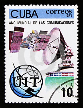 Cuba postage stamp shows sputnik, satellite antenna, globe and emblem, Year of comunication, circa 1983