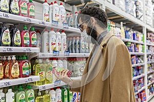 Moscow, Russia, 07/17/2020: A masked man in the household chemicals department in a large supermarket. Young brunette with a beard