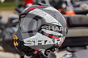 Moscow, Russia - May 04, 2019: Black sports motorcycle helmet Shark with red and white stripes and goggles on the handlebar of