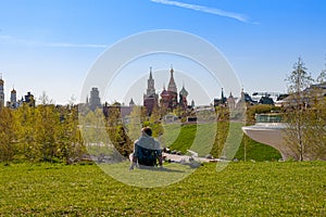 MOSCOW, RUSSIA - MAY 03, 2018: A girl lies in a spring meadow with a view of the Kremlin towers from Zaryadye park